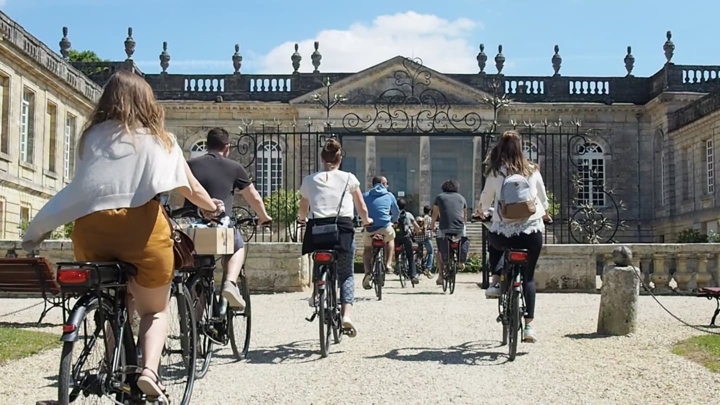 Des cyclistes devant les grilles d’un château de Saint-Émilion