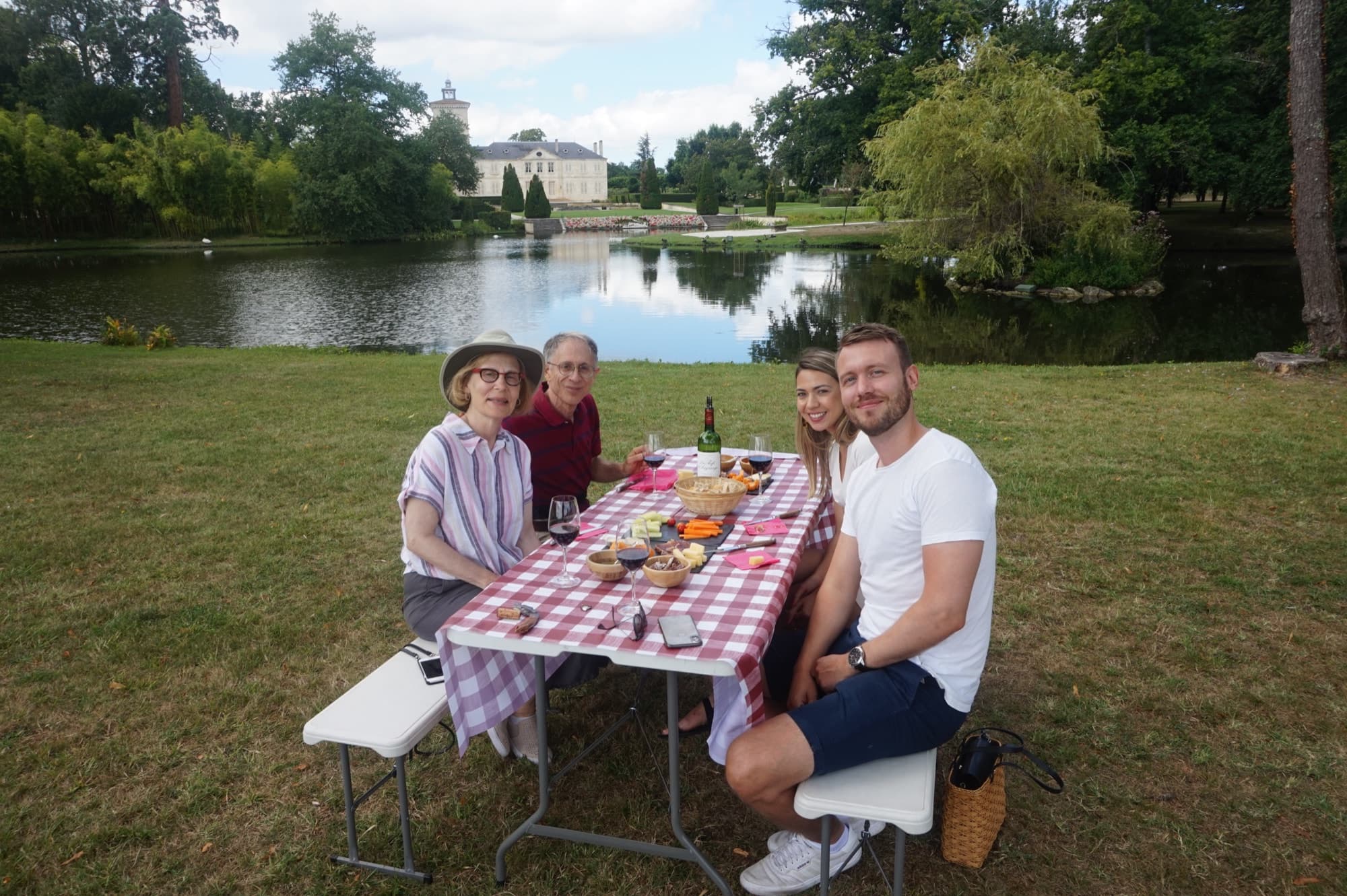 Des visiteurs partagent un pique-nique au bord du lac d’un château bordelais